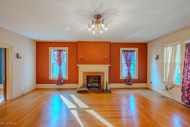 unfurnished living room with a brick fireplace and a chandelier