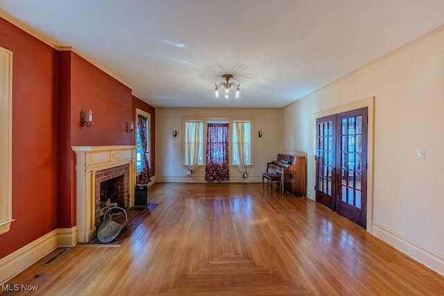 unfurnished living room with french doors, a brick fireplace, and an inviting chandelier