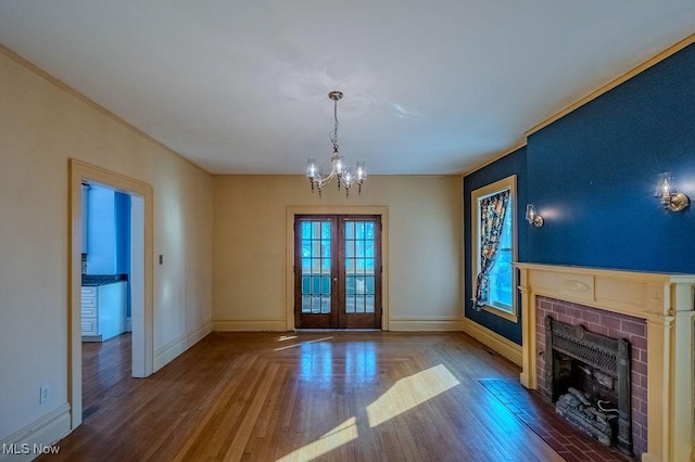 unfurnished living room with french doors, hardwood / wood-style floors, a fireplace, and a chandelier