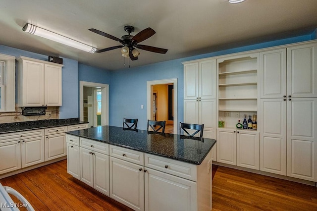 kitchen with a kitchen breakfast bar, white cabinetry, dark hardwood / wood-style flooring, and a kitchen island