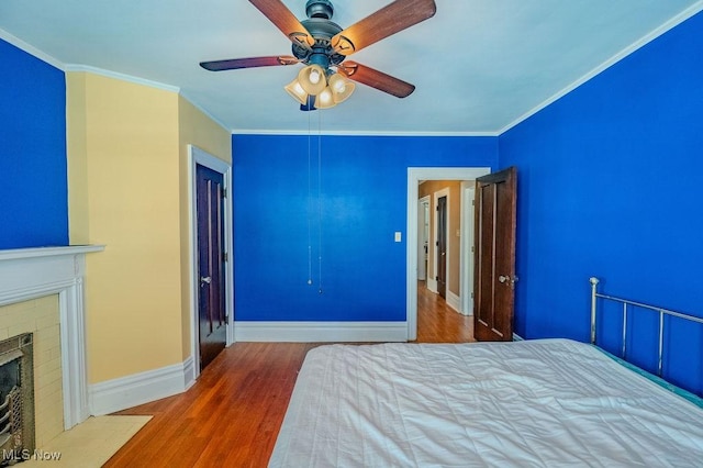 unfurnished bedroom featuring a closet, wood-type flooring, ceiling fan, ornamental molding, and a fireplace