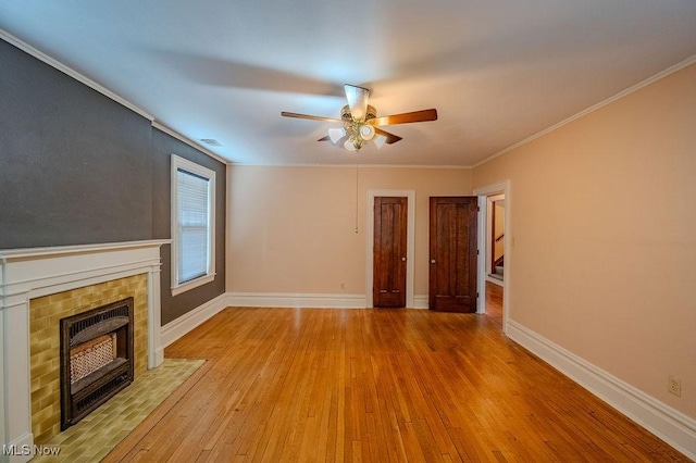 unfurnished living room with a tile fireplace, ceiling fan, crown molding, and light hardwood / wood-style flooring