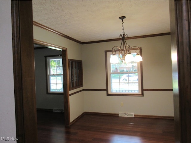 unfurnished dining area with a wealth of natural light, dark wood-type flooring, a chandelier, and a textured ceiling