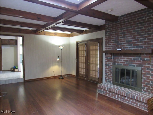 unfurnished living room with a brick fireplace, beam ceiling, and hardwood / wood-style floors