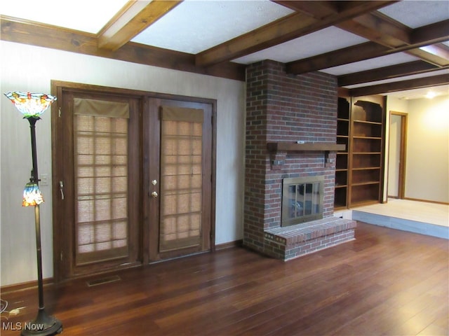 unfurnished living room with built in shelves, a fireplace, dark hardwood / wood-style flooring, and beamed ceiling