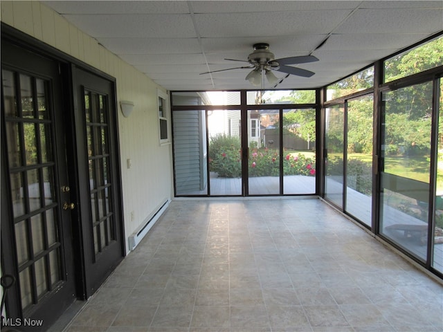 unfurnished sunroom featuring ceiling fan, a paneled ceiling, and baseboard heating