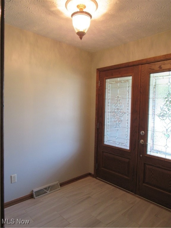 foyer featuring french doors and a textured ceiling