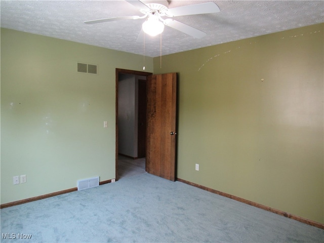 spare room featuring ceiling fan, light colored carpet, and a textured ceiling