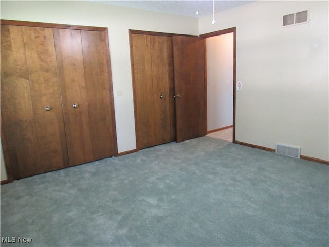 unfurnished bedroom featuring two closets and carpet flooring