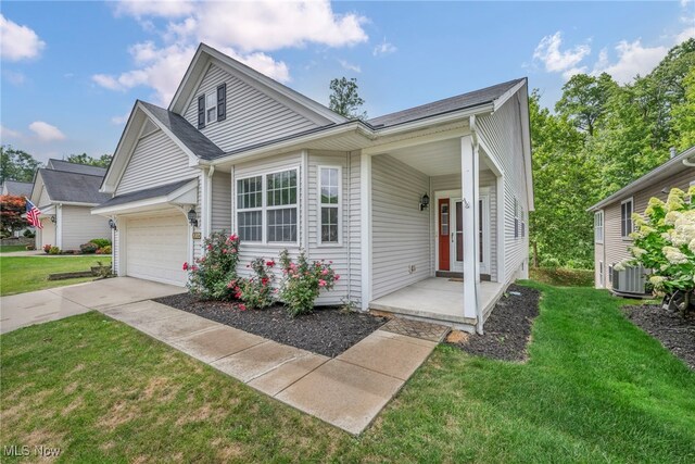 view of front of home with cooling unit, a garage, and a front lawn