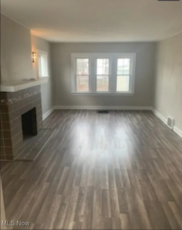 unfurnished living room featuring dark wood-type flooring and a fireplace