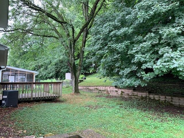 view of yard featuring a sunroom, a wooden deck, and central AC