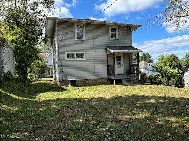 rear view of property with central AC unit and a yard