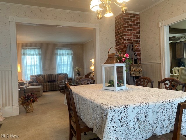 dining space with carpet flooring, crown molding, and a notable chandelier