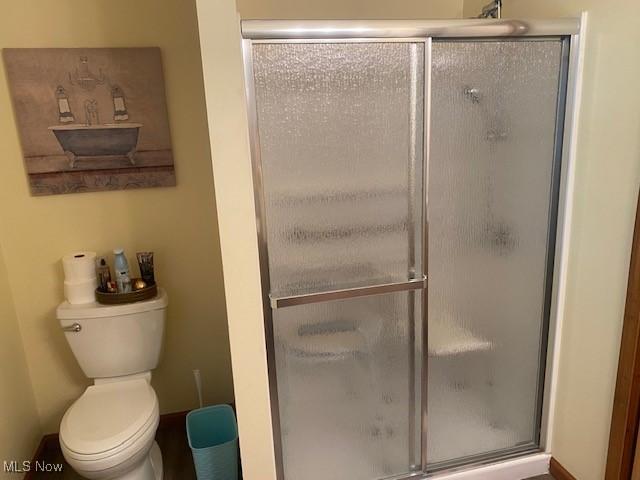 bathroom featuring toilet and an enclosed shower