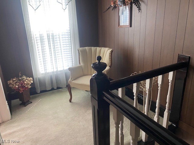 living area featuring wood walls and light carpet