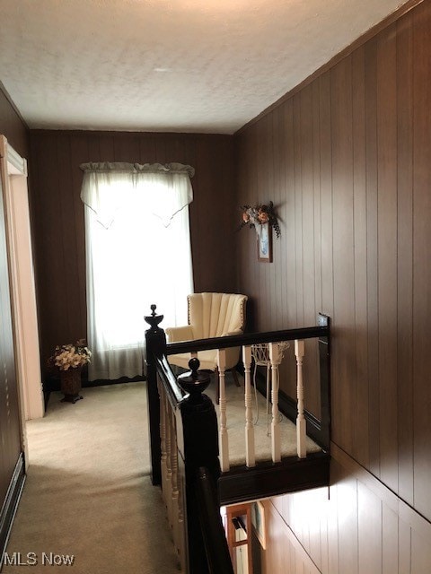 bedroom with light colored carpet, a textured ceiling, and wood walls