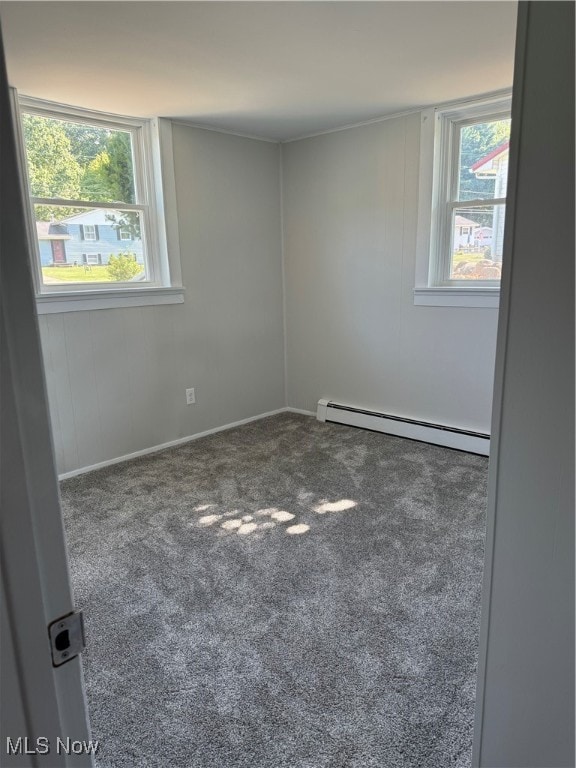 empty room featuring a baseboard heating unit, a healthy amount of sunlight, and carpet