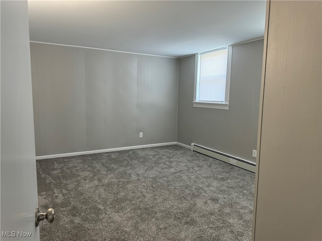 carpeted spare room with a baseboard heating unit