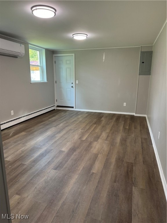 unfurnished room with a baseboard radiator, a wall unit AC, hardwood / wood-style flooring, and electric panel