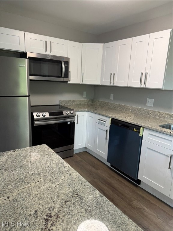 kitchen with appliances with stainless steel finishes, dark hardwood / wood-style flooring, light stone counters, and white cabinetry