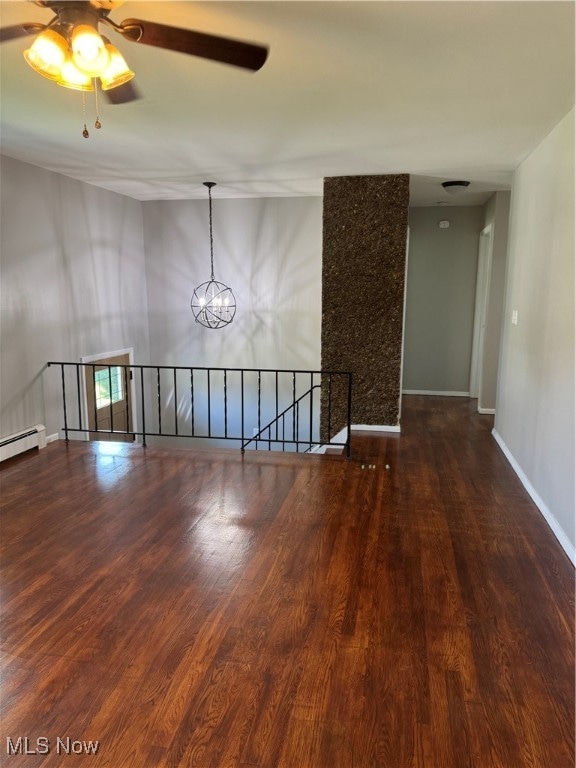 spare room featuring a baseboard radiator, ceiling fan with notable chandelier, and hardwood / wood-style floors