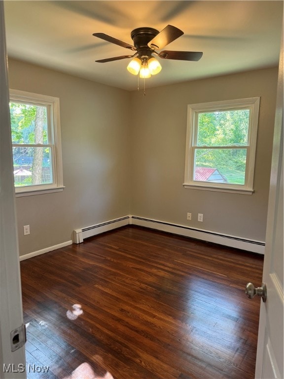 empty room featuring a wealth of natural light, ceiling fan, and dark wood-type flooring