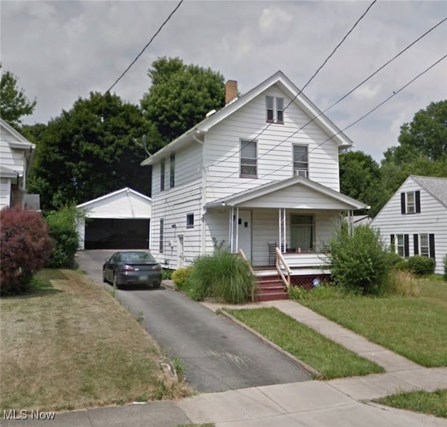 view of front of house with a porch, a garage, an outdoor structure, and a front yard