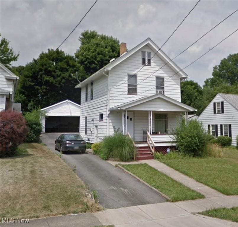 view of front of property with an outbuilding, a garage, a front lawn, and a porch