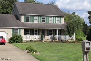 view of front of home featuring a garage, a front yard, and covered porch