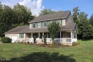 view of front of house featuring covered porch, a garage, and a front lawn