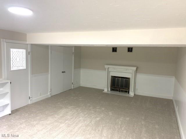 unfurnished living room featuring a fireplace and light carpet