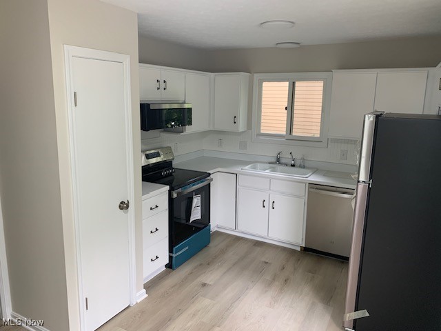 kitchen with light wood-type flooring, sink, stainless steel appliances, and white cabinetry