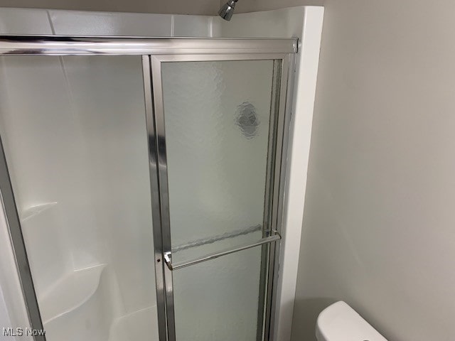 bathroom with a shower with door and toilet