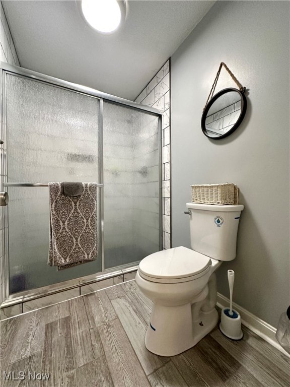 bathroom with walk in shower, toilet, and wood-type flooring