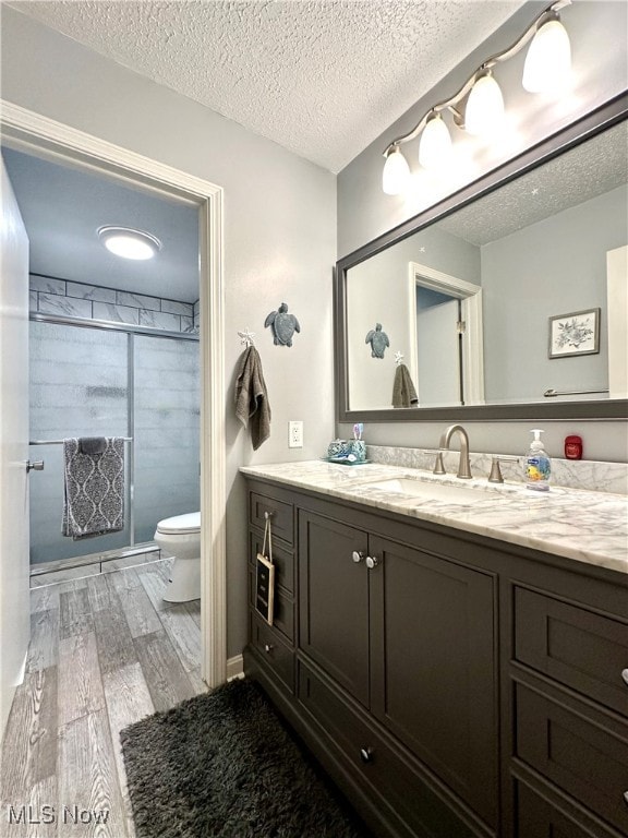 bathroom with vanity, a textured ceiling, toilet, and hardwood / wood-style floors