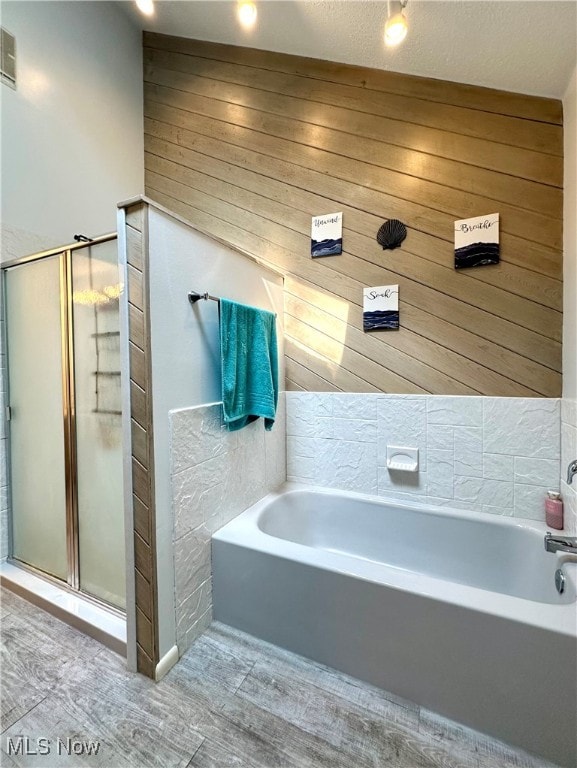 bathroom featuring wood walls, a textured ceiling, vaulted ceiling, and independent shower and bath