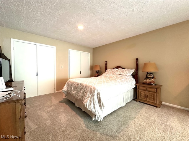 carpeted bedroom with two closets and a textured ceiling