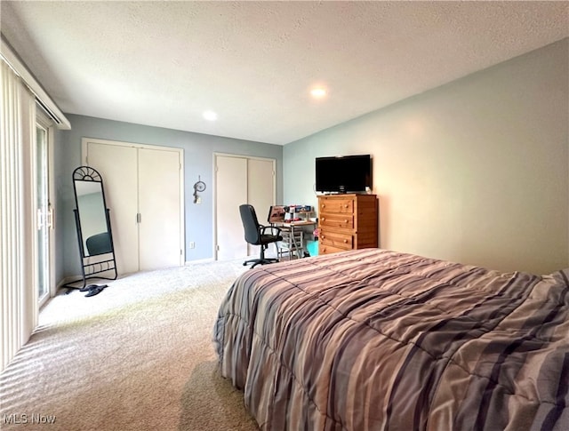 carpeted bedroom featuring multiple closets and a textured ceiling