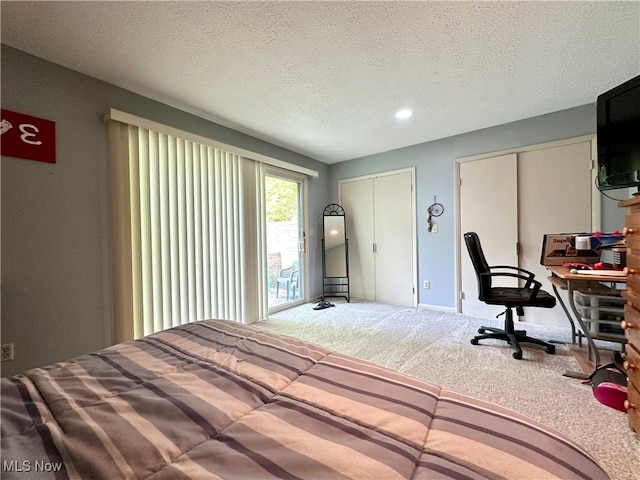 bedroom with a textured ceiling, carpet flooring, and two closets