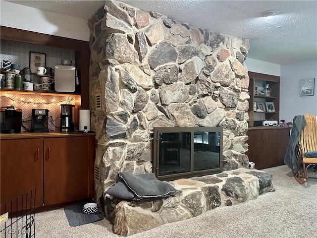 living room with a textured ceiling, light colored carpet, and a stone fireplace