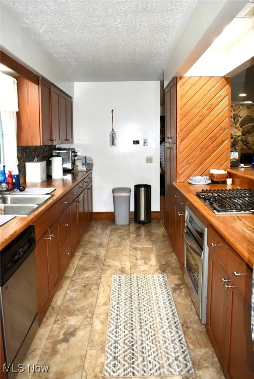 kitchen with appliances with stainless steel finishes, a textured ceiling, light tile patterned floors, and sink