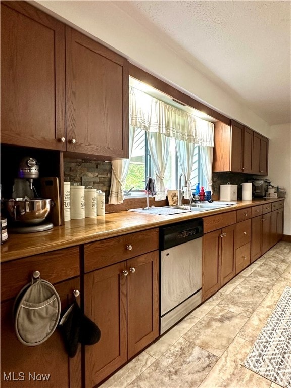 kitchen with decorative backsplash, a textured ceiling, white dishwasher, light tile patterned floors, and sink