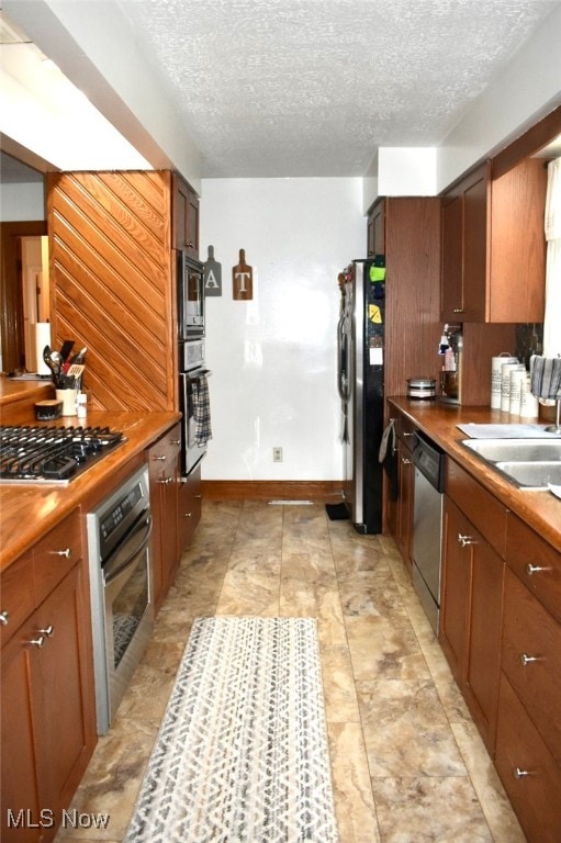 kitchen featuring sink, stainless steel appliances, a textured ceiling, and light tile patterned floors