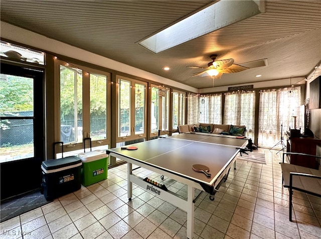 game room featuring a skylight, light tile patterned floors, and ceiling fan