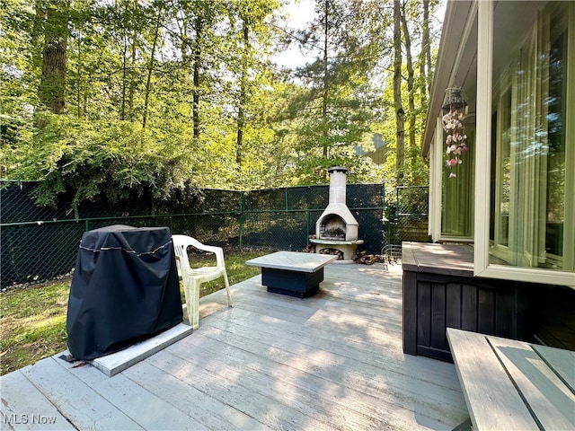 wooden terrace with a fireplace and area for grilling