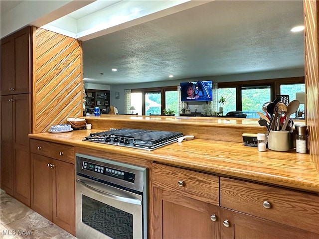 kitchen with stainless steel appliances, a textured ceiling, light tile patterned floors, and a wealth of natural light