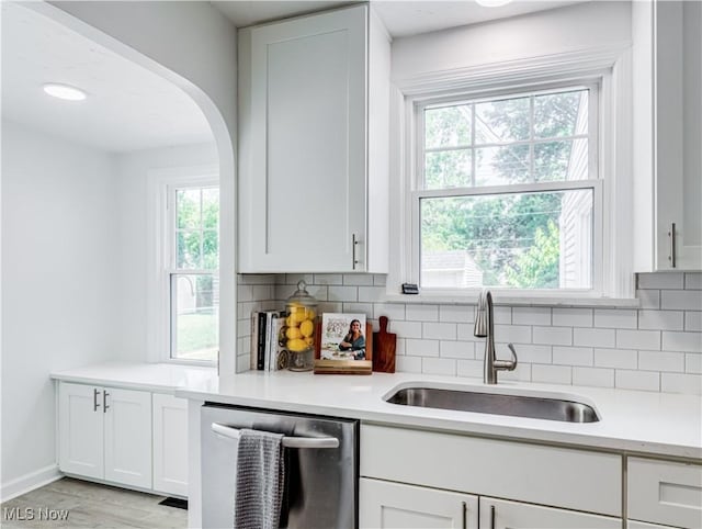 kitchen with light countertops, stainless steel dishwasher, and white cabinetry