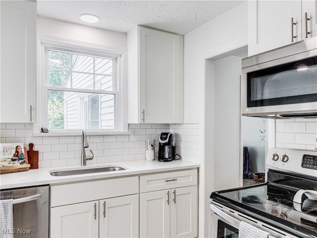 kitchen with stainless steel appliances, a sink, light countertops, and white cabinetry