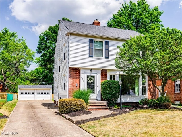 colonial home with brick siding, a chimney, a detached garage, an outbuilding, and a front yard